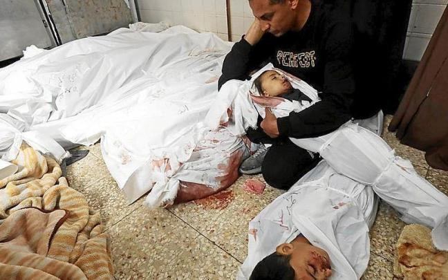 Un hombre sostiene en brazos el cadáver de su hijo muerto en una morgue de un hospital de Gaza. | FOTO: E.P.