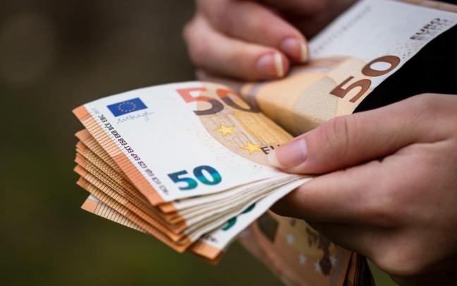 Una persona sostiene un fajo de billetes.