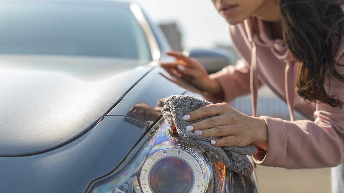 Chica revisa la carrocería del coche después de un pequeño golpe.