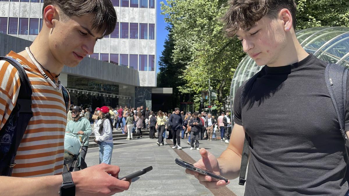 Dos jóvenes tratan de comunicarse a través de sus móviles tras el apagón del pasado lunes 28 de abril.