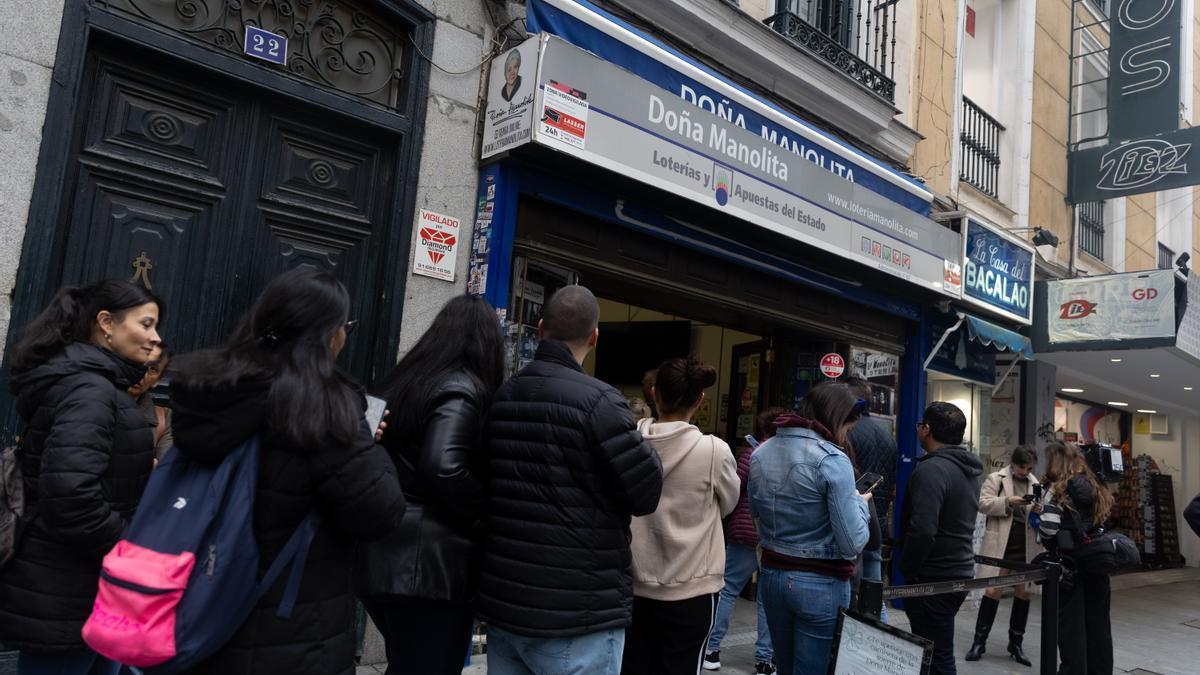 Un grupo de personas hace cola para comprar sus décimos en la administración de Lotería de Doña Manolita, en Madrid.