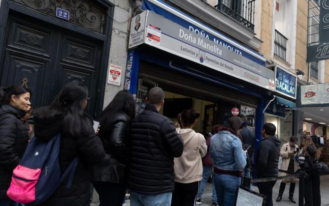 Un grupo de personas hace cola para comprar sus décimos en la administración de Lotería de Doña Manolita, en Madrid.