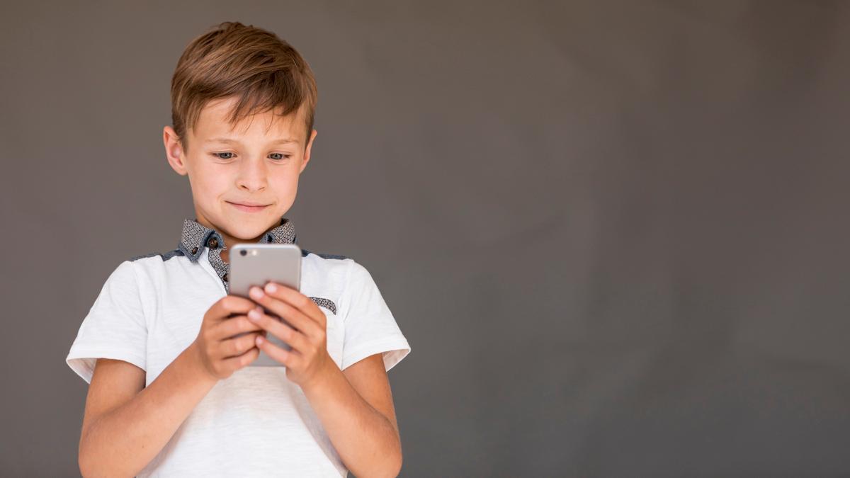 Un niño mira con atención la pantalla de su móvil.