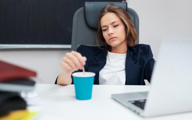 Una mujer revuelve un café con desgana.