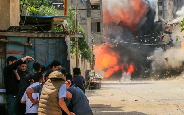 Varias personas se cubren mientras un misil impacta en un edificio en Gaza. Varias personas se cubren mientras un misil impacta en un edificio en Gaza.