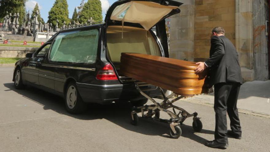 Un trabajador de una funeraria introduce un ataud en un cementerio.