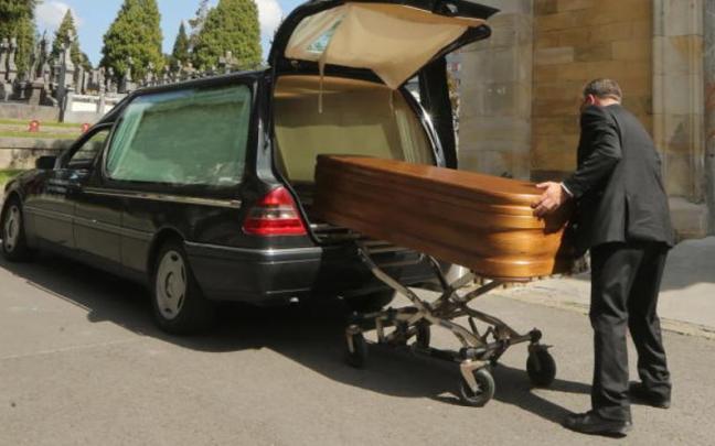 Un trabajador de una funeraria introduce un ataud en un cementerio. Un trabajador de una funeraria introduce un ataud en un cementerio.