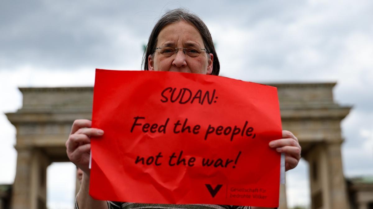 Una mujer sostiene un cartel en Alemania en el que pide alimentar a la gente en Sudán, no la guerra.