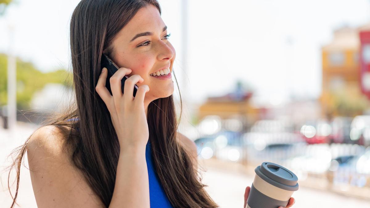 Una joven usa el teléfono móvil para hacer una llamada y hablar con un amigo.