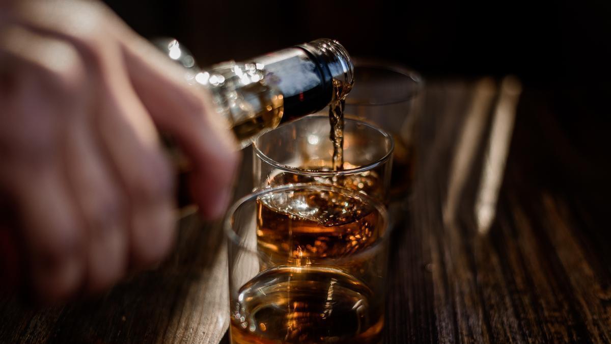 Un hombre sigue varios vasos de Whiskey.
