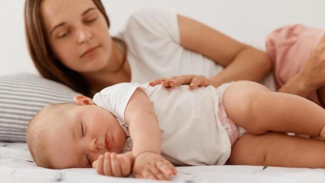 Madre durmiendo a su bebé.