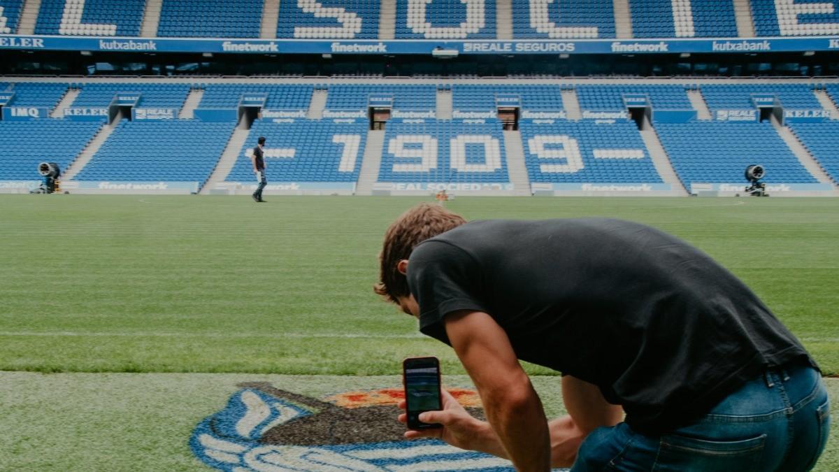 Una persona fotografía el escudo de la Real en el césped de Anoeta. / R.S.