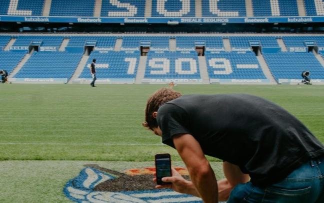 Una persona fotografía el escudo de la Real en el césped de Anoeta. / R.S.
