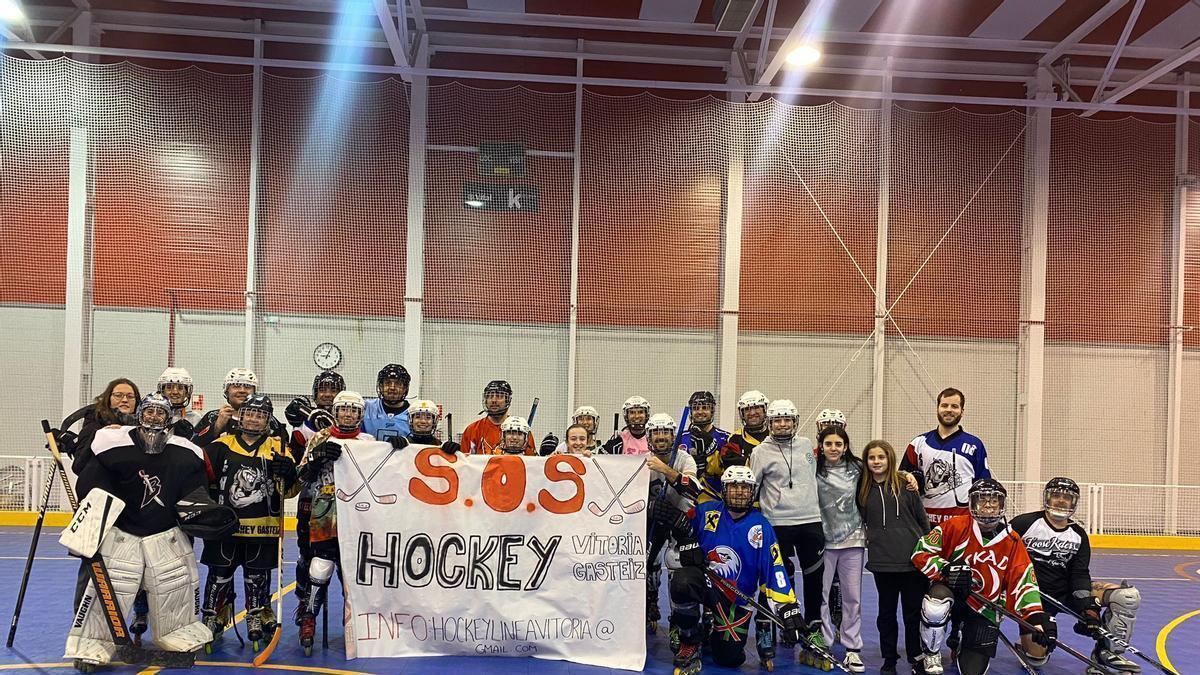 Varios jugadores de hockey línea posan en la pista de Olaranbe con una pancarta con el nombre de la plataforma