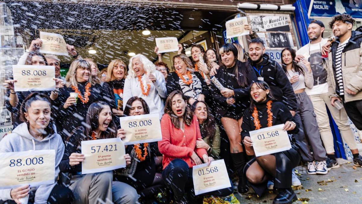 Grupo de personas celebrando que les ha tocado la Lotería de Navidad en la puerta de la administración donde compraron el décimo