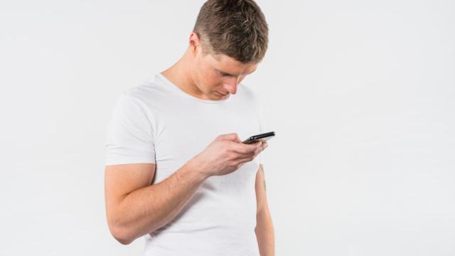 Un joven mira el móvil con la cabeza agachada.
