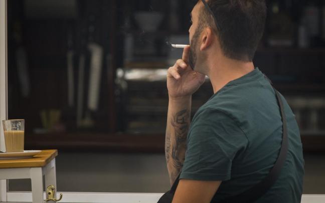 Un hombre fumando en una terraza.
