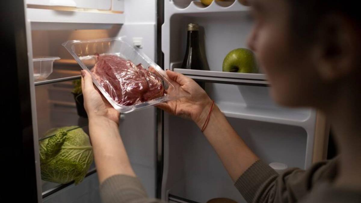 Mujer sacando carne envasada de la nevera
