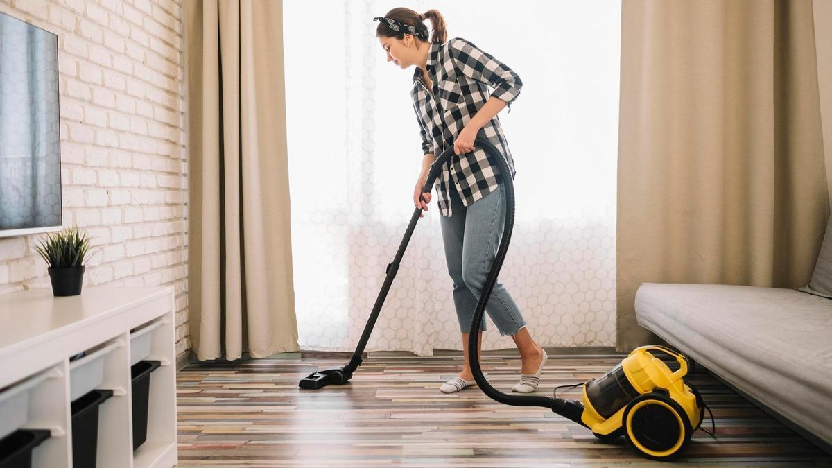 Una mujer pasa el aspirador por la sala de estar.