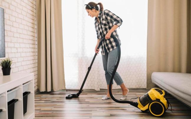 Una mujer pasa el aspirador por la sala de estar.