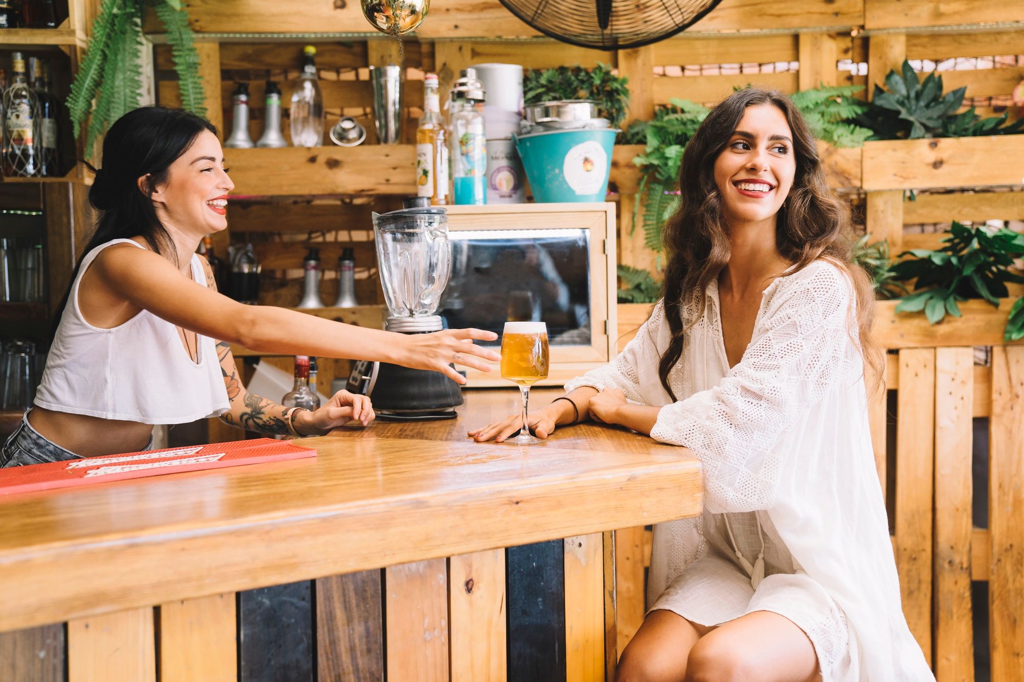 Una mujer toma una cerveza en un chiringuito playero.