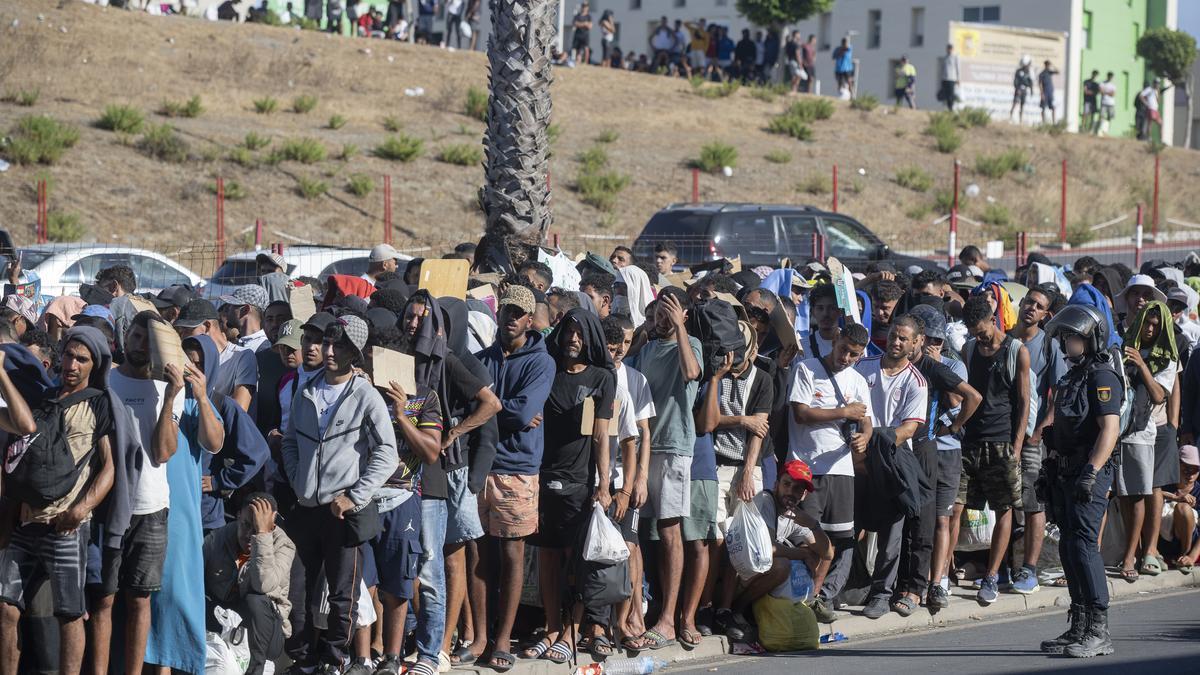 Migrantes esperan en una cola en Ceuta.