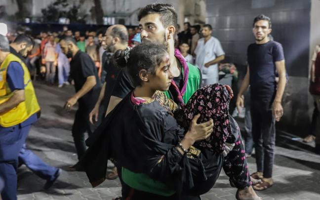 Un hombre lleva en brazos a una niña herida en el ataque al hospital.