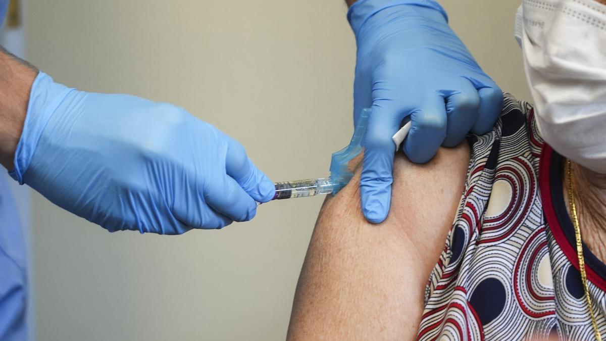 Un enfermero administra la vacuna de la gripe a una paciente.