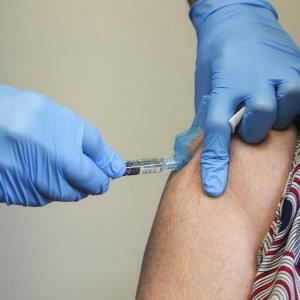 Un enfermero administra la vacuna de la gripe a una paciente.