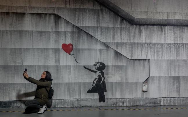 Varias personas recorren la exposición permanente de las obras de Banksy, en el Museo Banksy de Madrid.