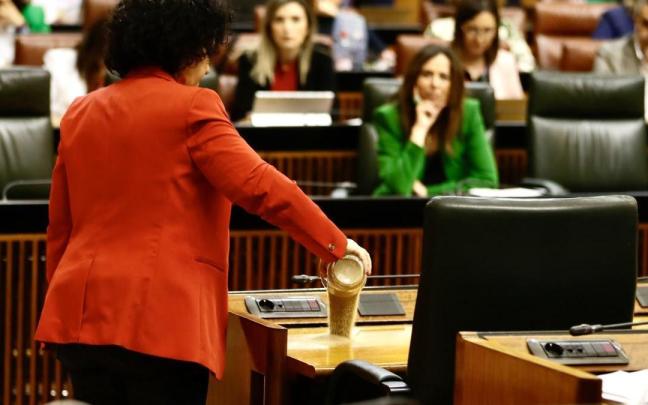 La diputada del Grupo Mixto Maribel Mora derrama arena en el escaño del presidente de la Junta, Juanma Moreno, durante el pleno del Parlamento andaluz.