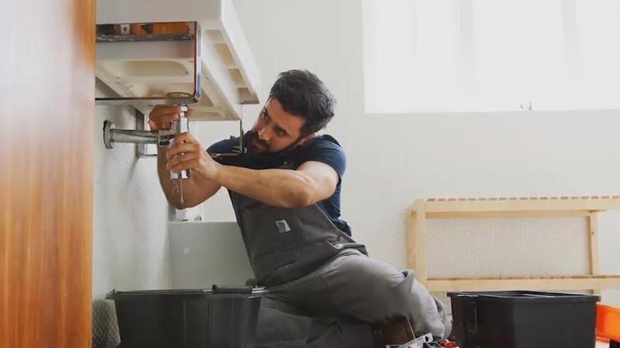 Un fontanero repara el desagüe de un lavabo.