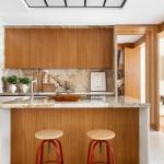 La cocina, con una gran isla central, está separada por unos paneles de madera y vidrio.