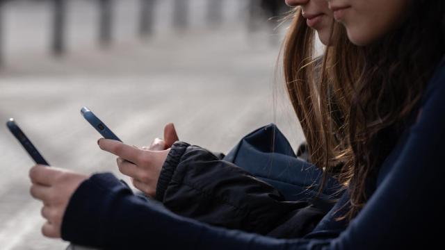Dos personas usan el teléfono móvil.
