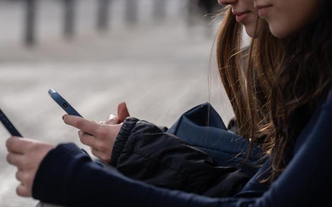 Dos personas usan el teléfono móvil.