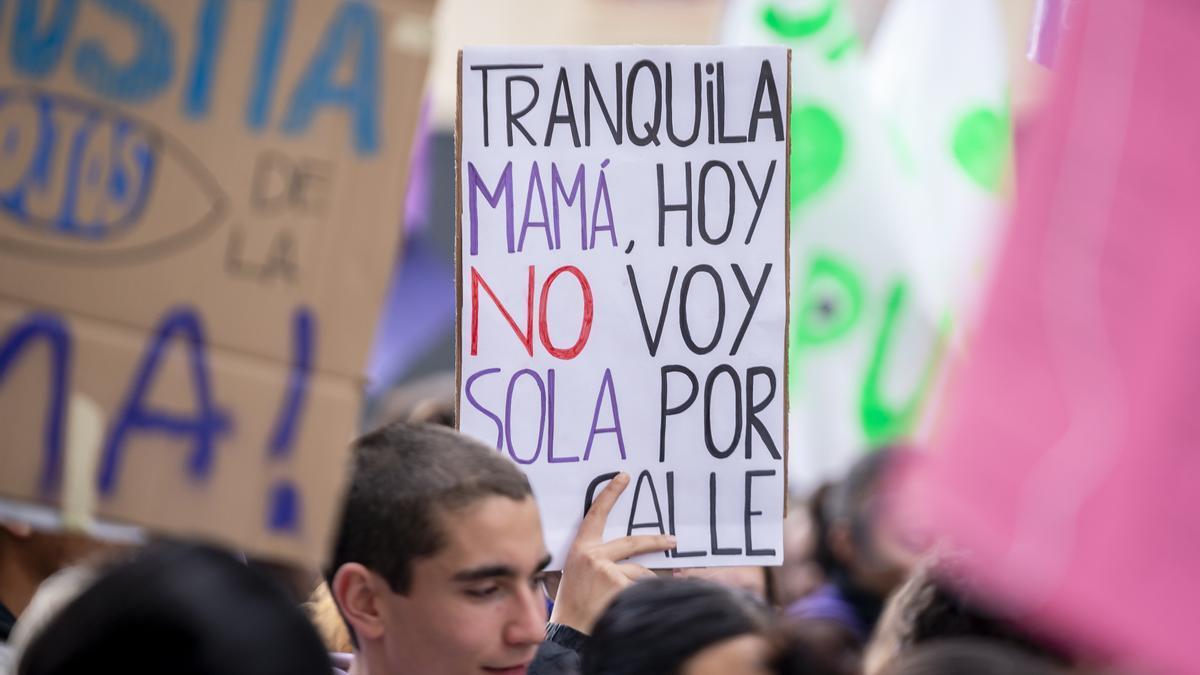 Una joven sujeta una pancarta con la frase: "Tranquila mamá, hoy no voy sola por la calle".