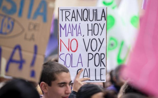 Una joven sujeta una pancarta con la frase: "Tranquila mamá, hoy no voy sola por la calle".