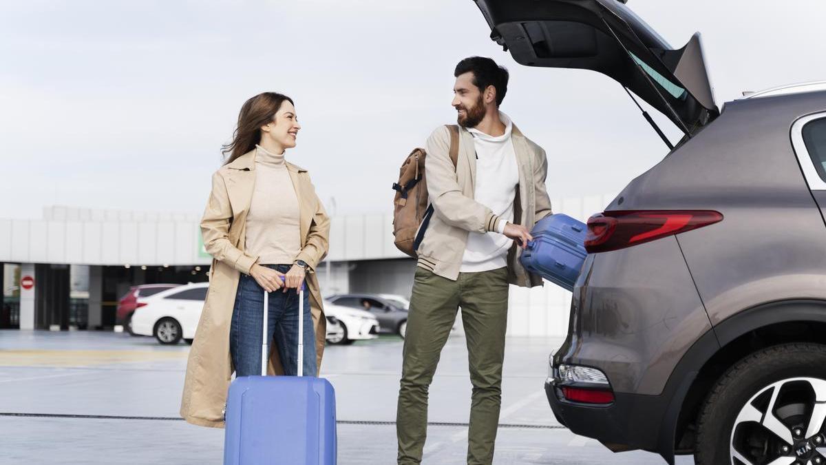 Pareja mete las maletas en el maletero del coche antes de comenzar su viaje.