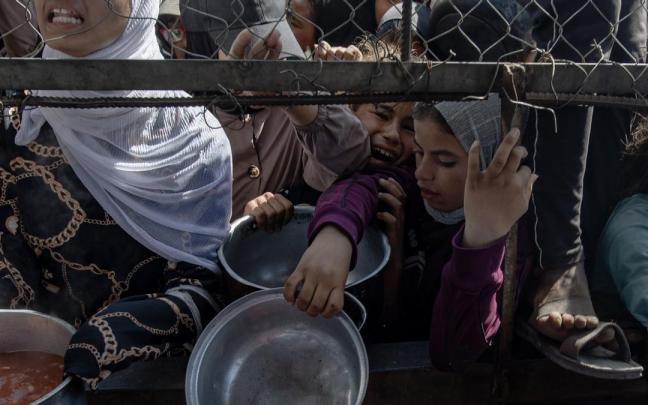 Refugiados palestinos recogen alimentos en la Franja de Gaza.