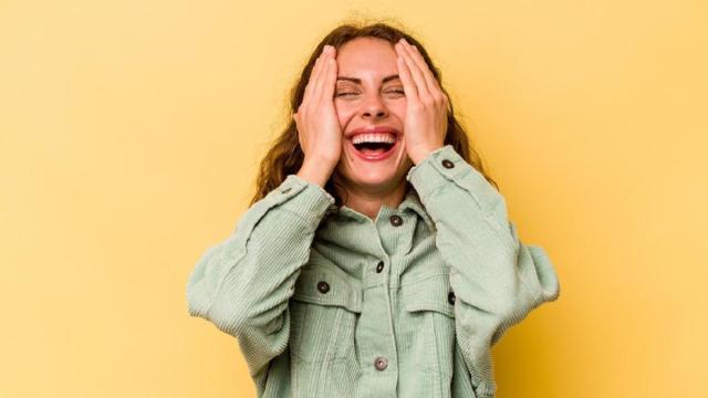Una mujer se tapa las mejillas para evitar que se le vea el sonrojo.