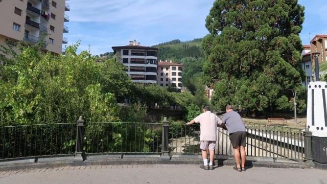 Dos vecinos observan el río Urola, desde uno de los puentes que une Urretxu y Zumarraga.