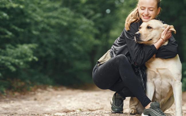 Una mujer abraza a su perro.