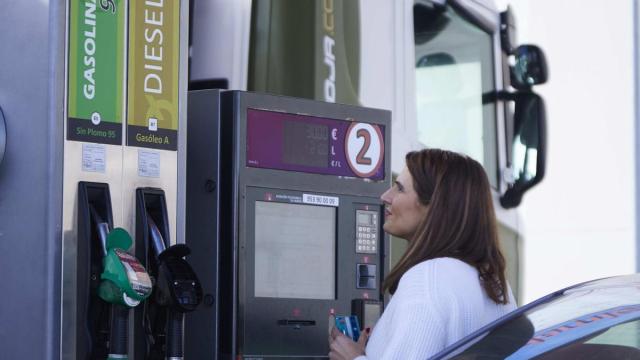 Una mujer paga en una gasolinera autoservicio en un momento de escalada de precios