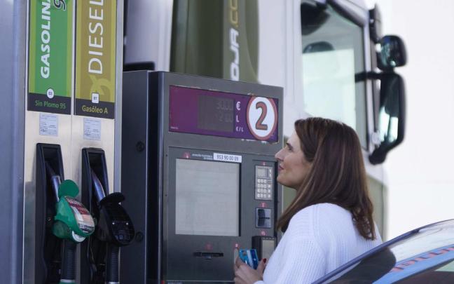 Una mujer paga en una gasolinera autoservicio en un momento de escalada de precios