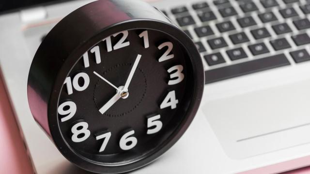 Un reloj analógico marca la hora sobre un teclado.