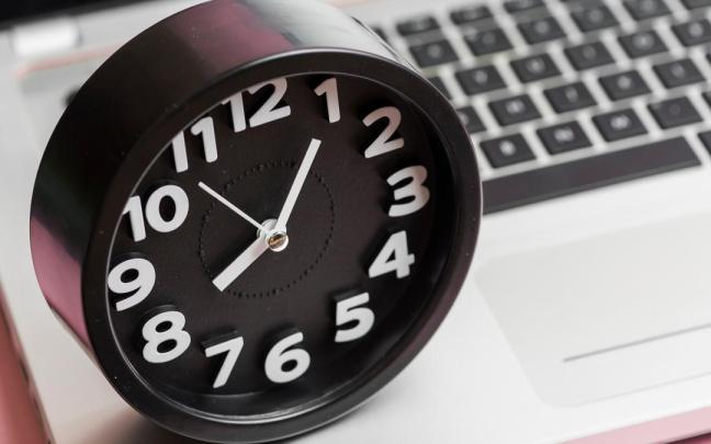 Un reloj analógico marca la hora sobre un teclado.