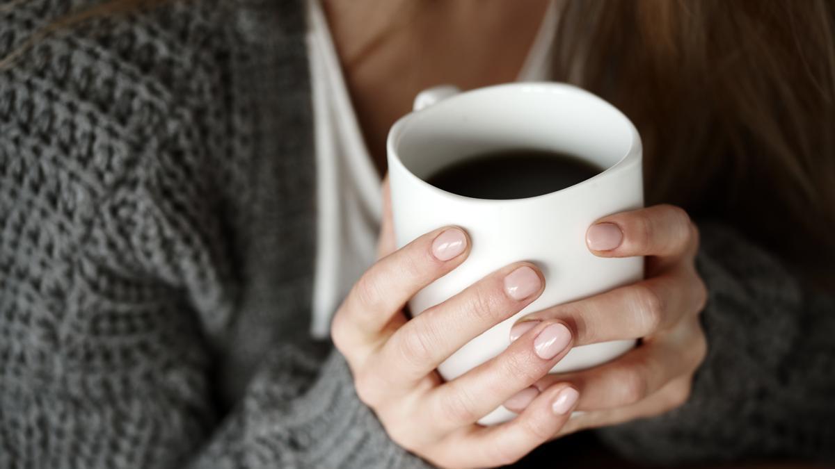 Primer plano de las manos de una chica con una taza de café