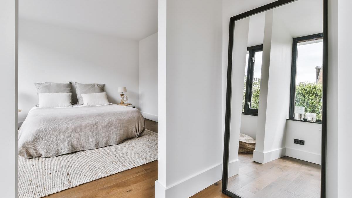 Habitación con un espejo colocado estratégicamente enfrente de una ventana para generar mayor sensación de amplitud y luz a la vivienda.