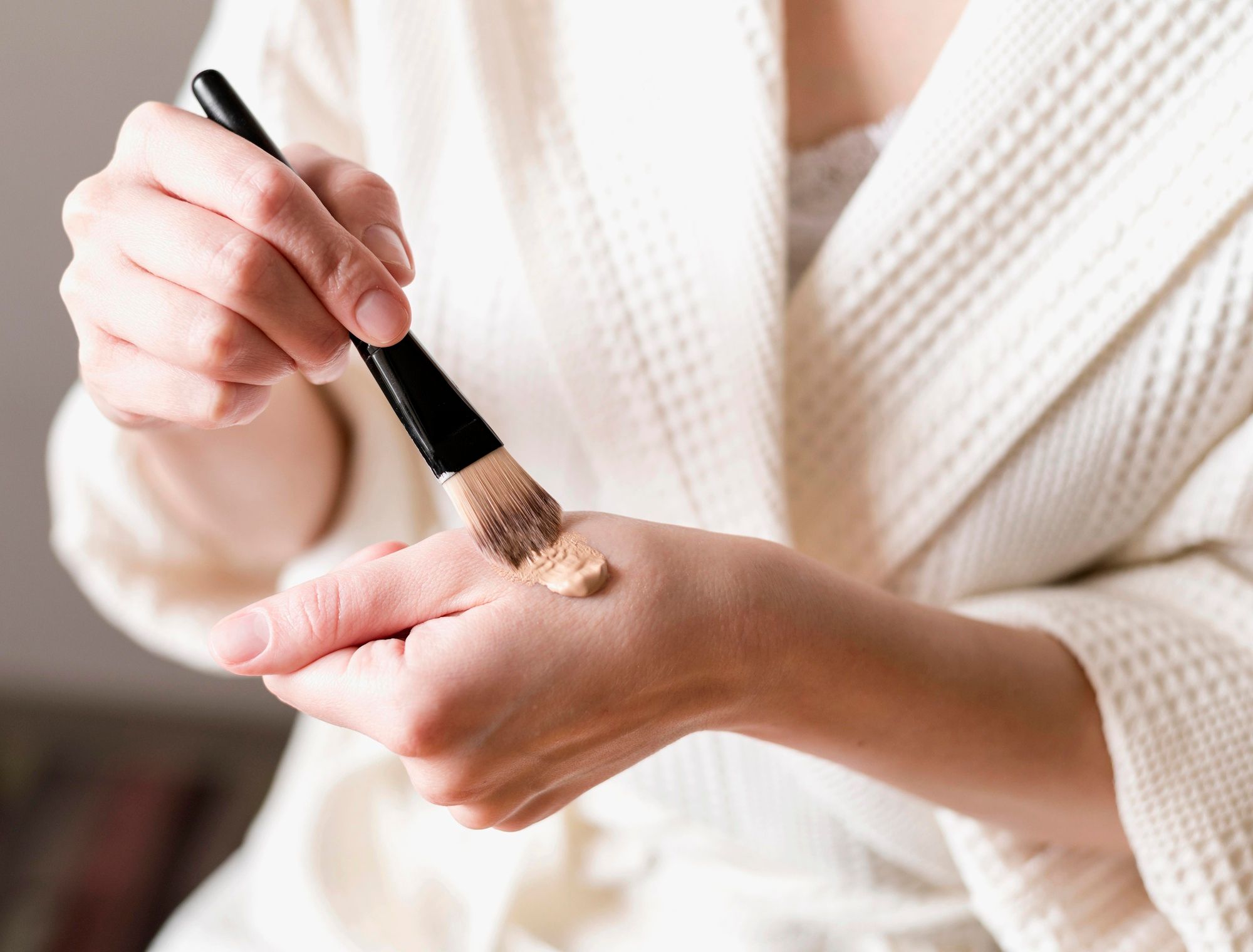 Una mujer coge corrector de su mano con una brocha.