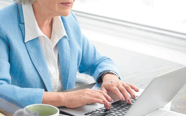 Una mujer jubilada realiza gestiones administrativas con un ordenador portátil.